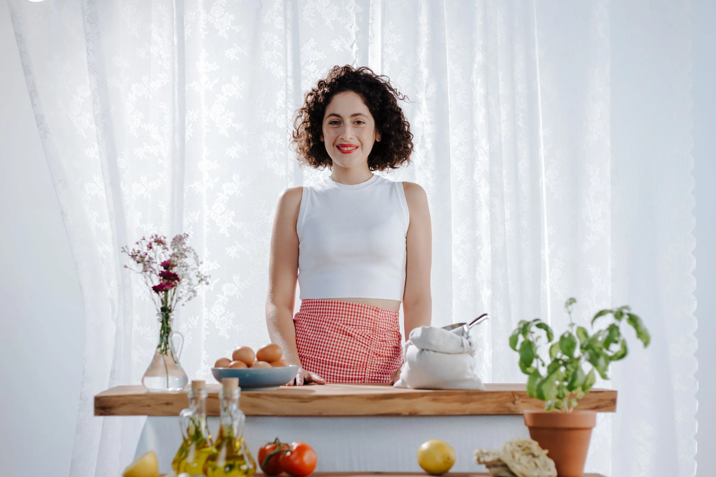 Smiling woman with fresh ingredients in a bright kitchen
